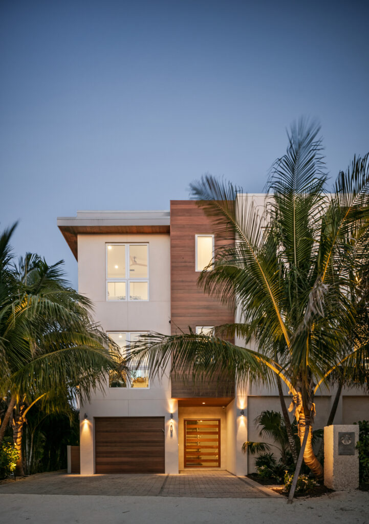 Front of Sundowner Beach with wood siding and palms at dusk