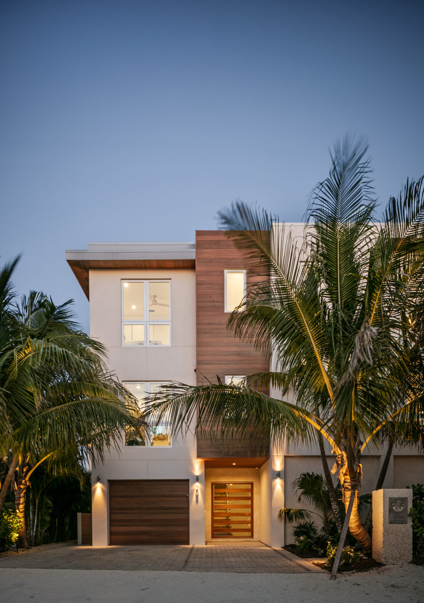 Front of Sundowner Beach with wood siding and palms at dusk