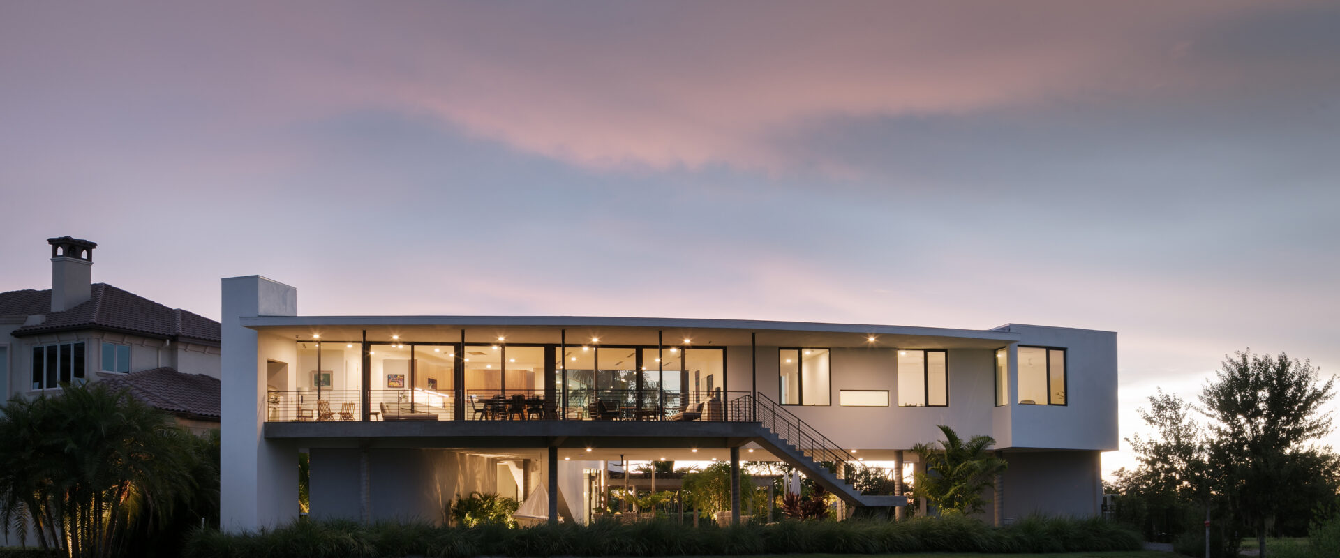 Palma Sola Modern at dusk from the lawn, glass walls lit