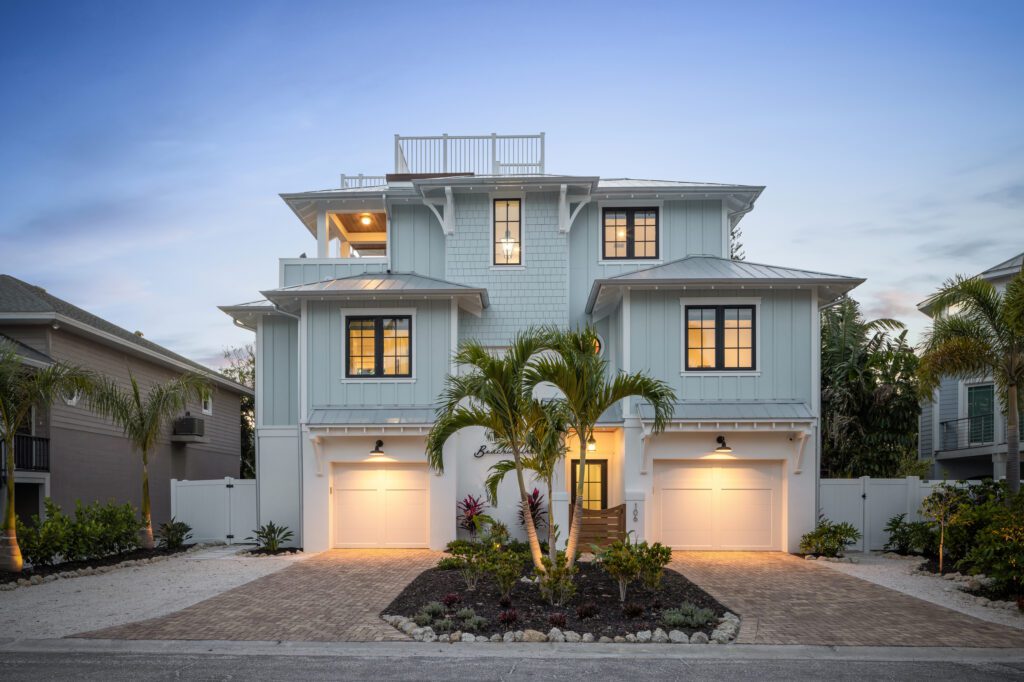 Beachwalker, a three-story blue-gray beach house with a rooftop deck, at dusk
