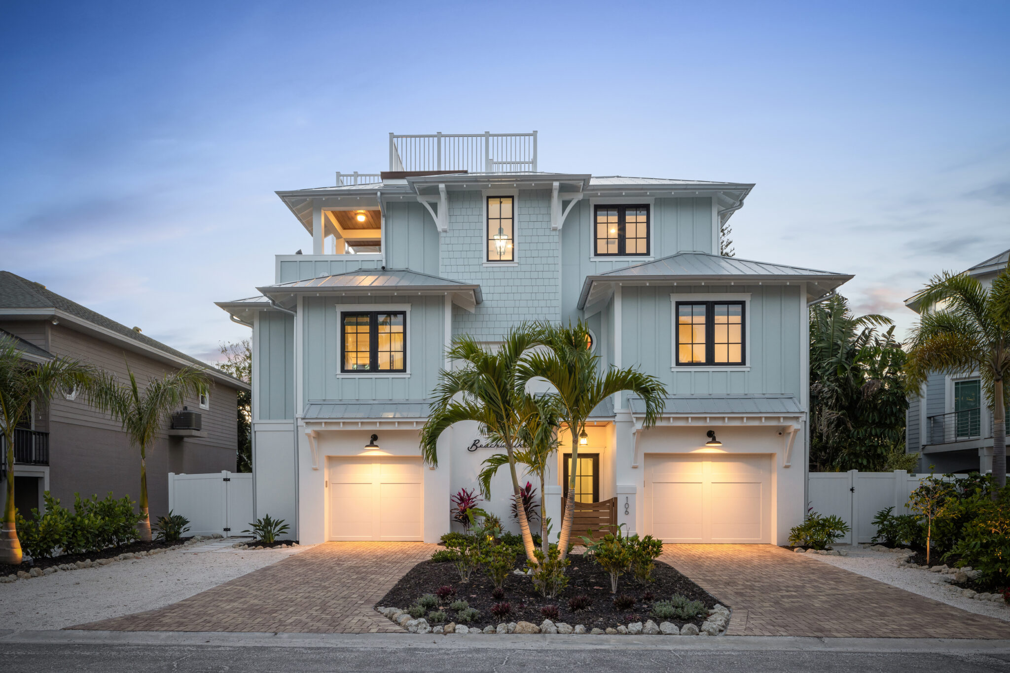 Beachwalker, a three-story blue-gray beach house with a rooftop deck, at dusk