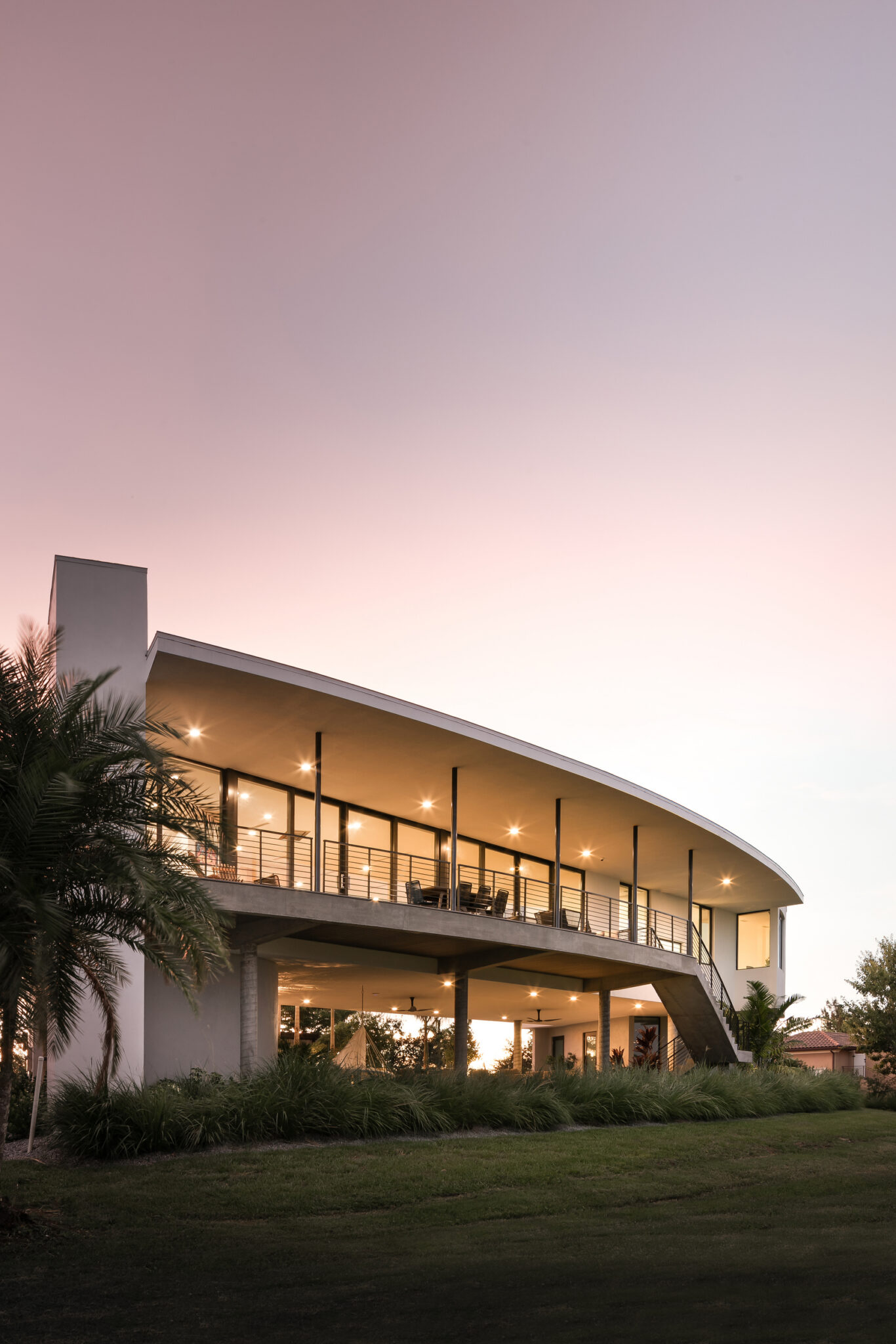 Curved roofline and glass of Palma Sola Modern at sunset
