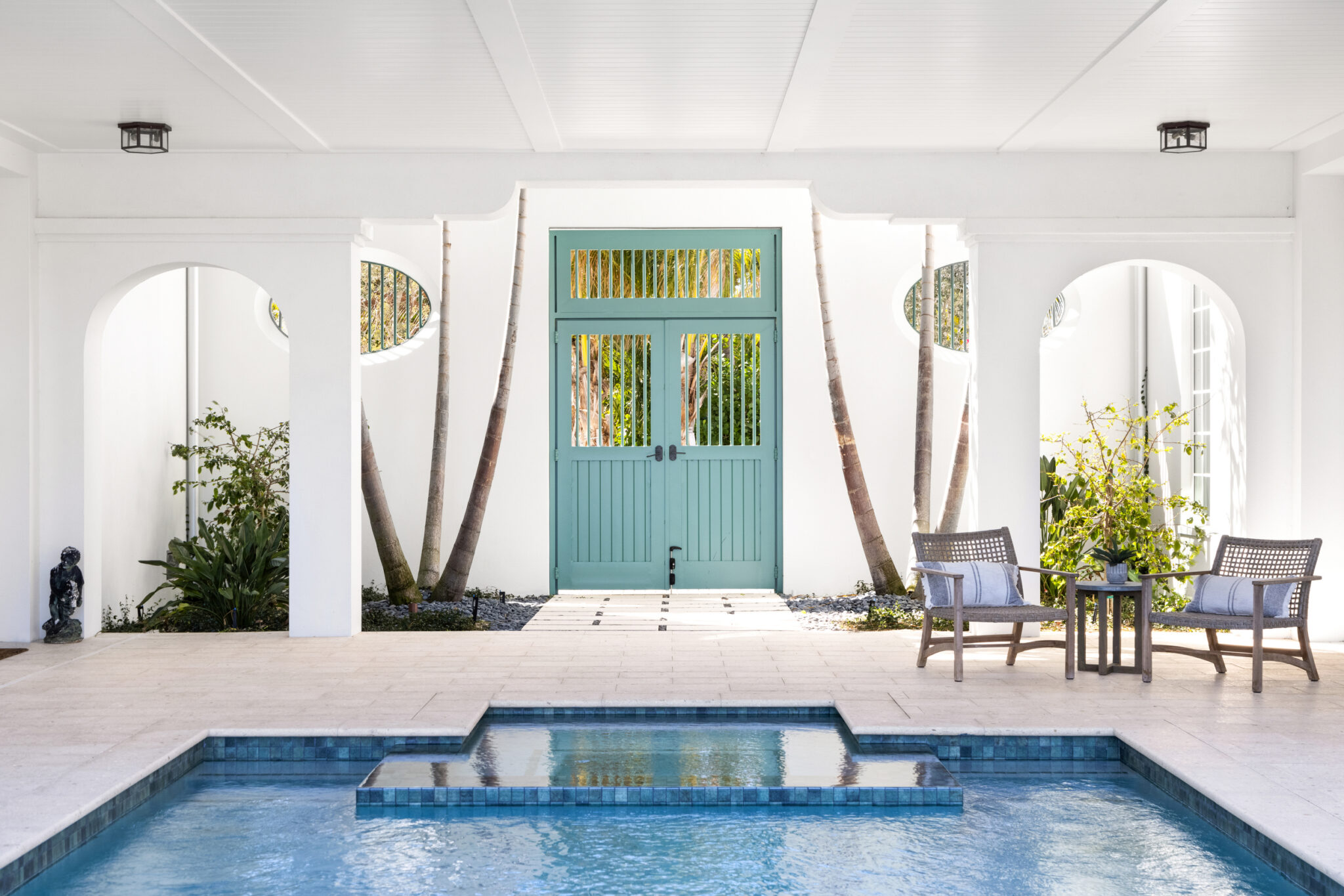 Courtyard pool with green entry doors and arched openings