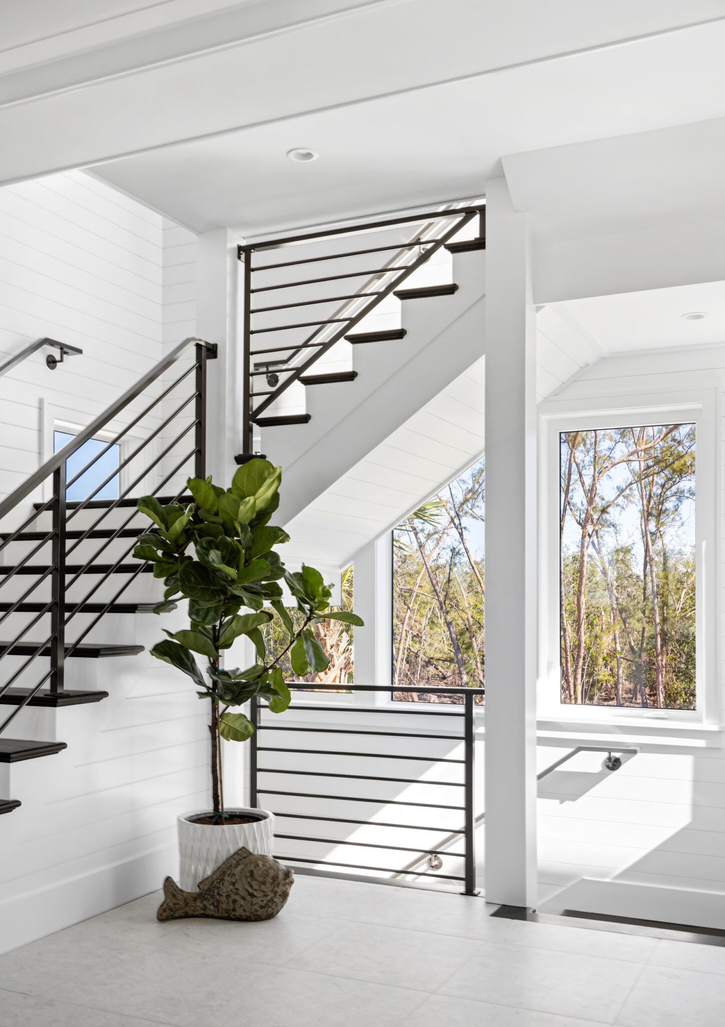 Black steel open stair with a fiddle-leaf fig