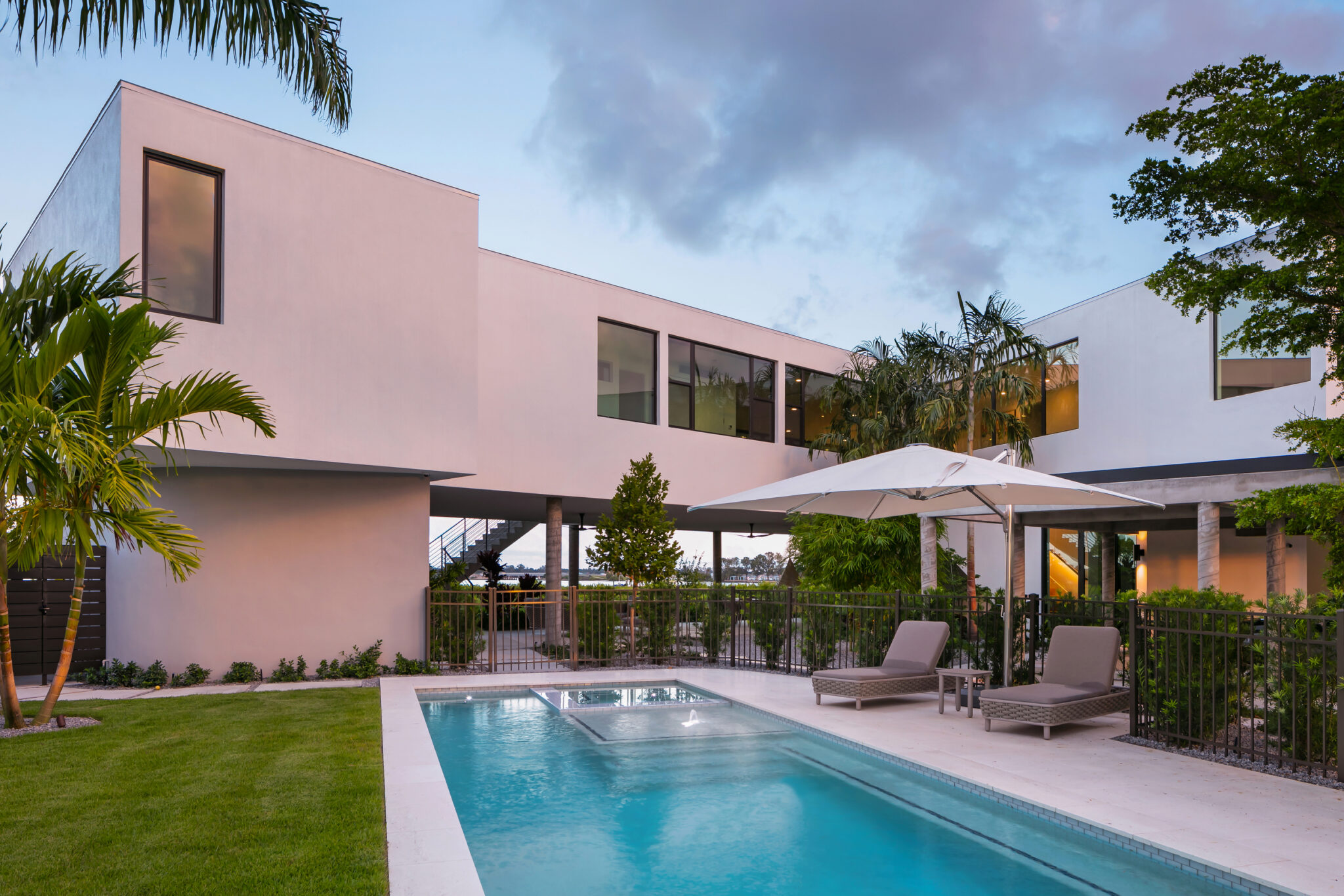 Pool and lounge chairs beside the white modern wings of the house