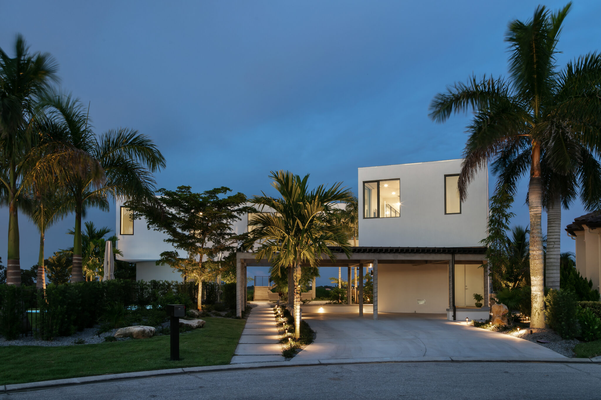 Front of Palma Sola Modern at dusk with palms and a lit drive