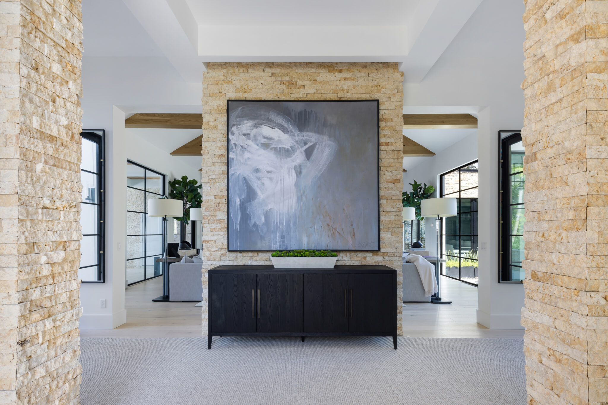 Entry with a stacked stone column, black console and large painting
