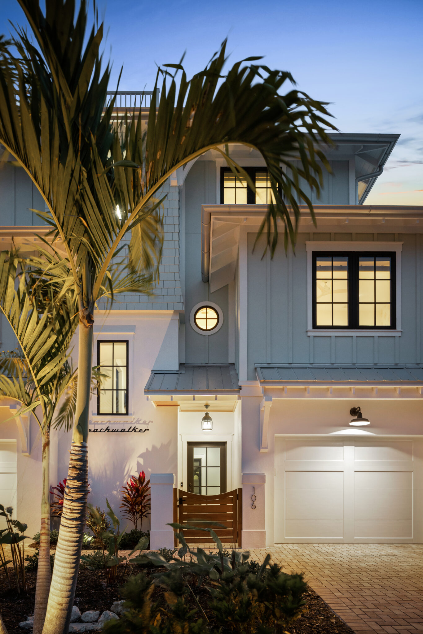 Corner of the house with palms and the garage at dusk