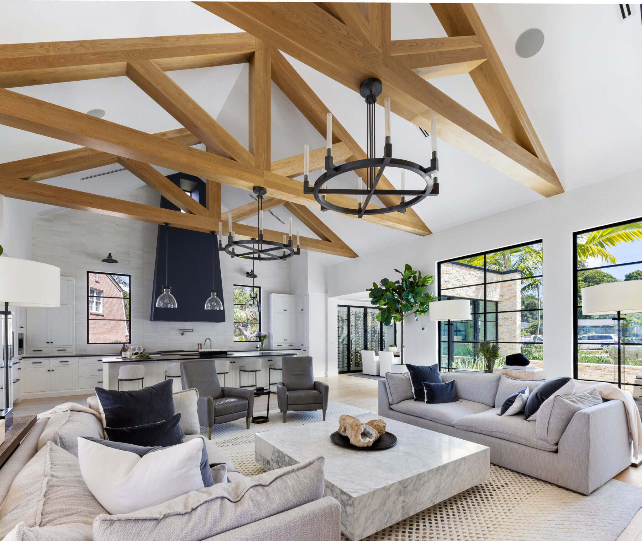 Great room under exposed timber trusses with a black iron chandelier