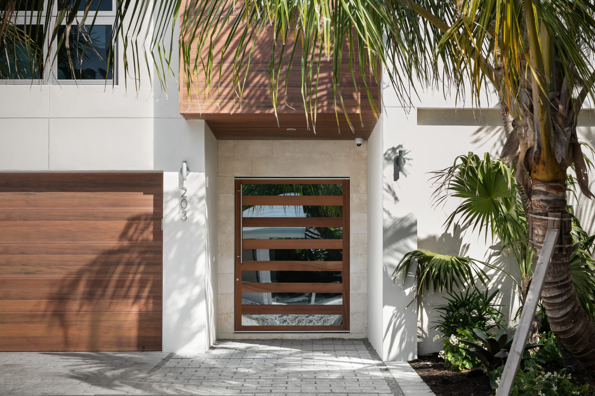 Entry with a wood pivot door and wood garage door