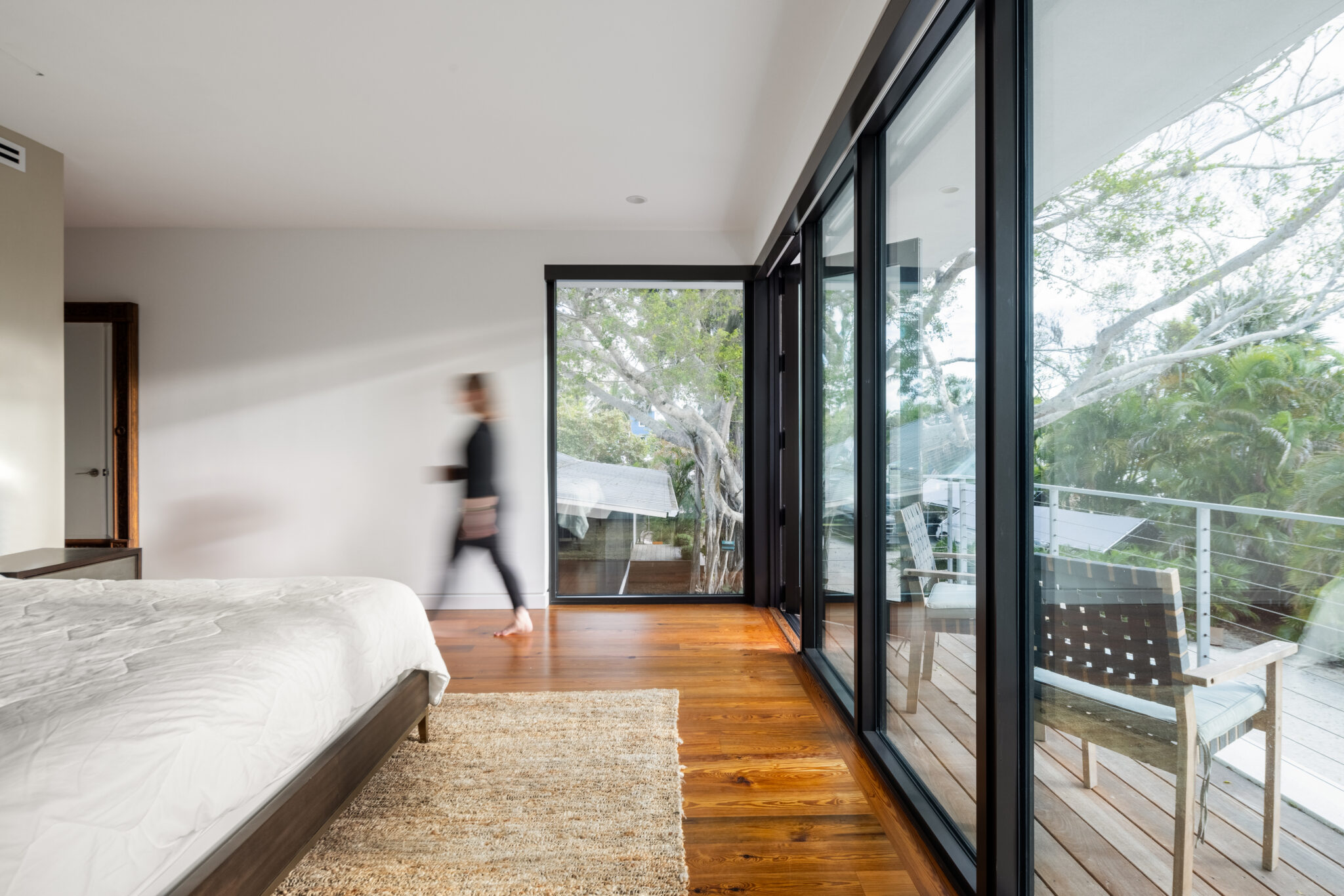 Corner bedroom with glass walls opening to the balcony