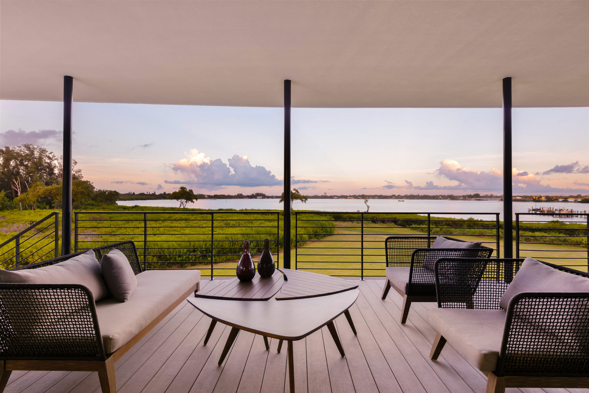 Covered balcony seating overlooking Palma Sola Bay at sunset