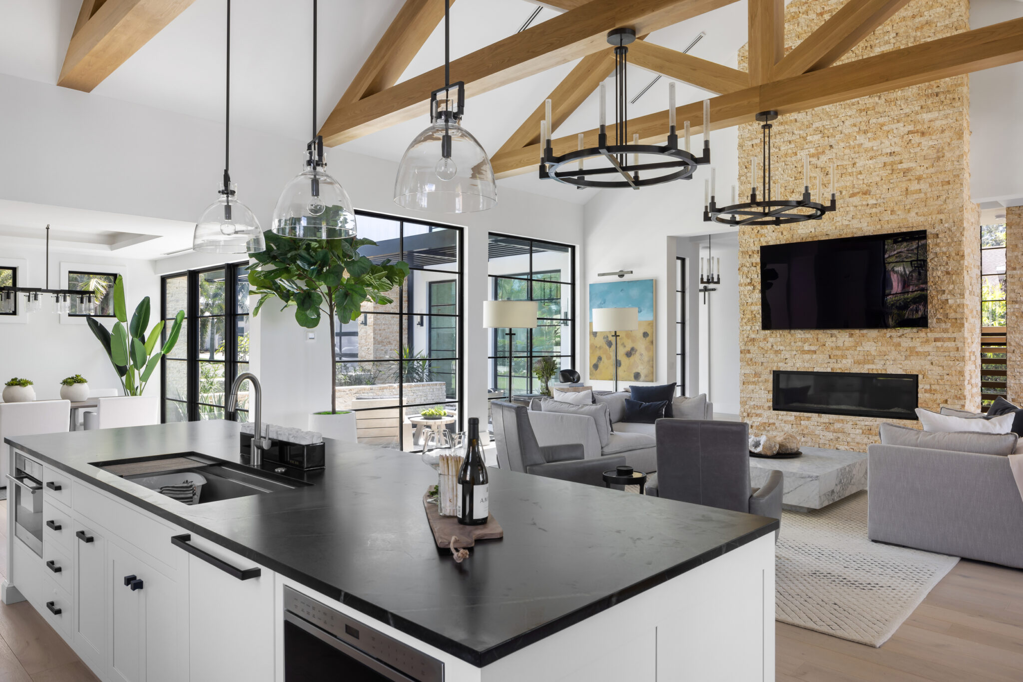 Kitchen island with a black counter, living room and stone fireplace beyond
