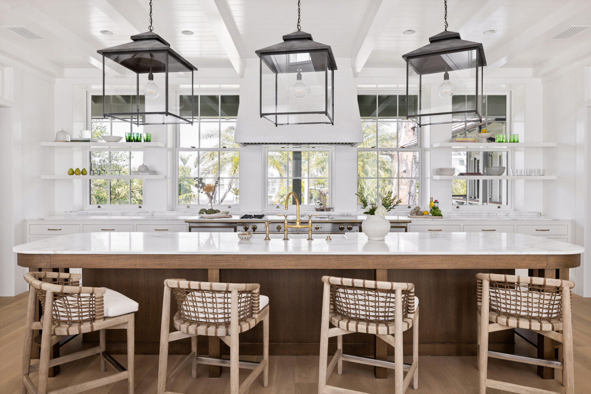 Kitchen island with woven counter stools under black lantern pendants