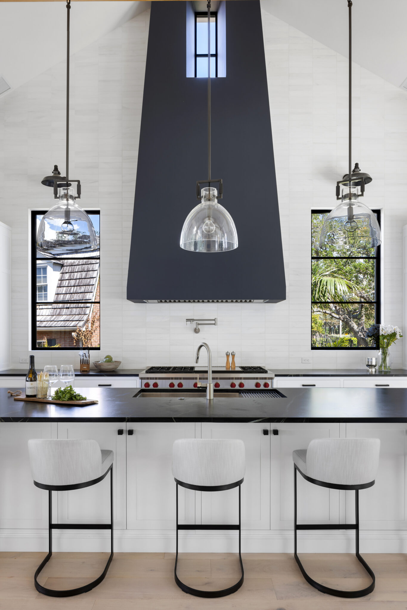 Kitchen with a black hood, black counters and white bar stools