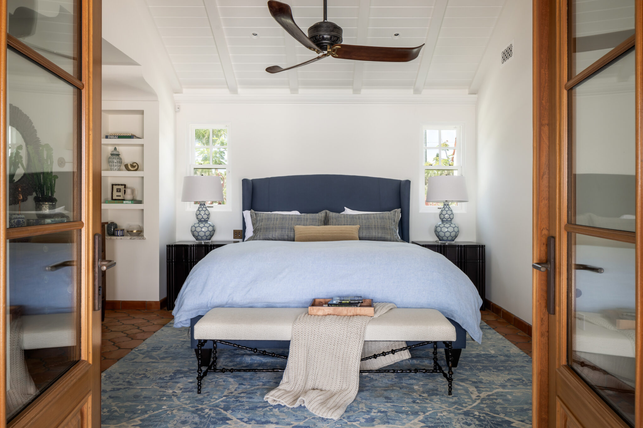 Bedroom with a navy upholstered bed seen through wood French doors