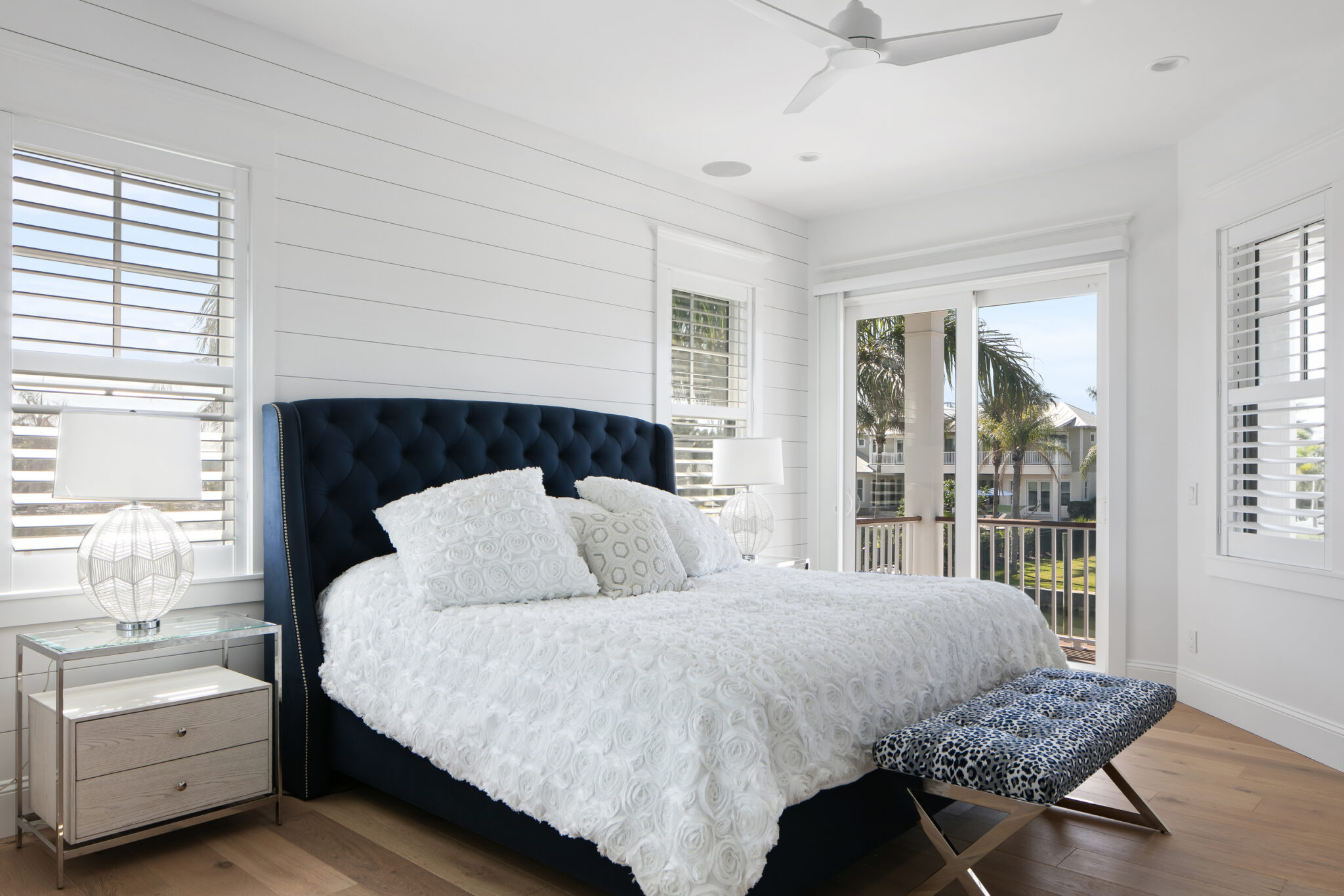 Bedroom with a navy tufted bed and French doors to a porch