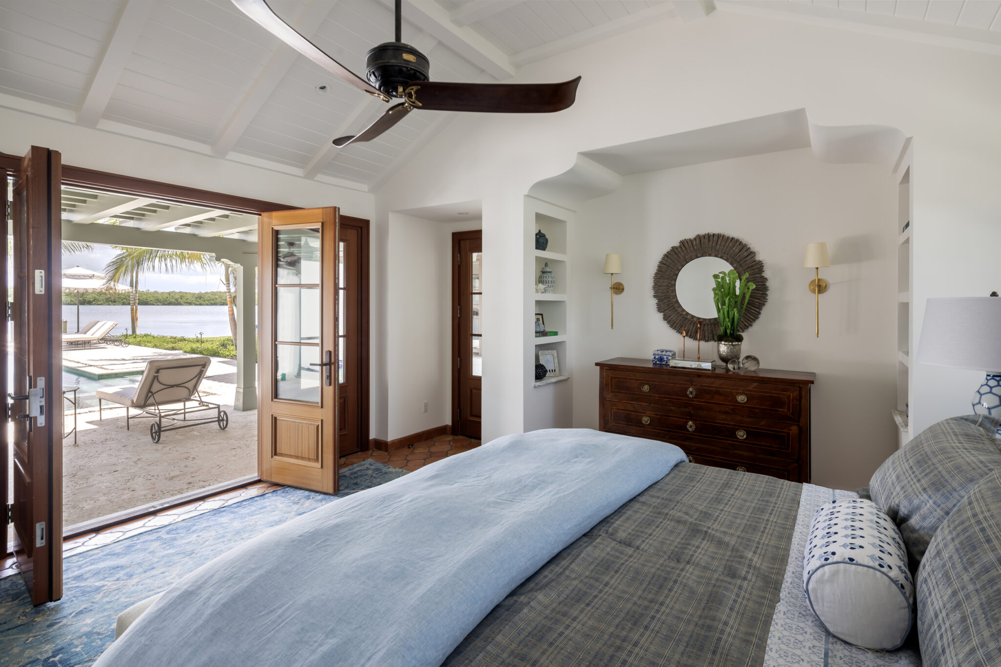 Bedroom opening through wood doors to a covered patio