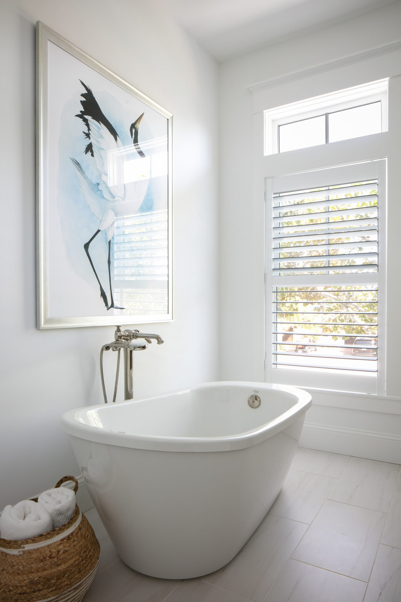 Freestanding tub beside a window with plantation shutters