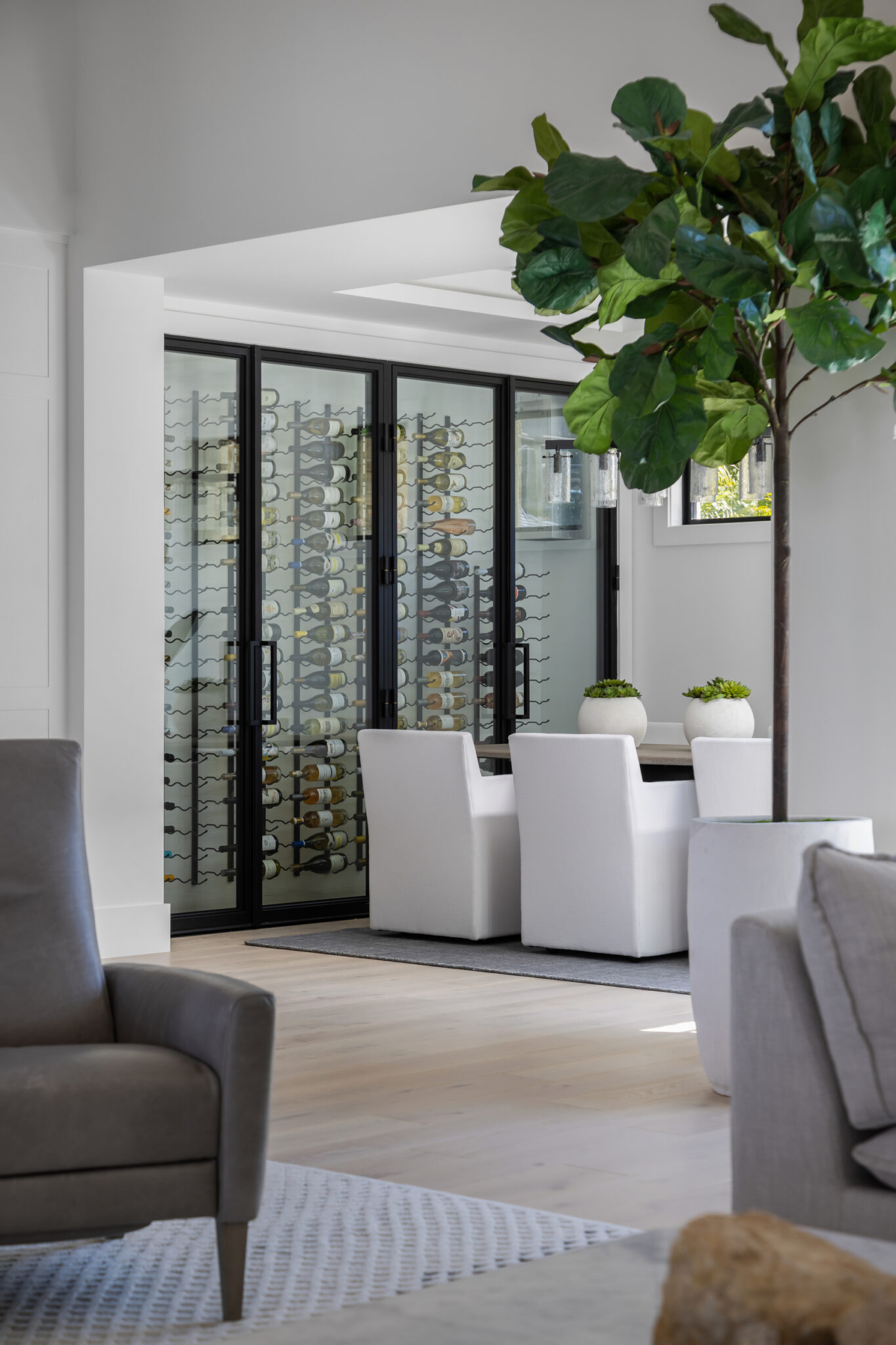 Dining area seen past a fiddle-leaf fig and steel-framed glass