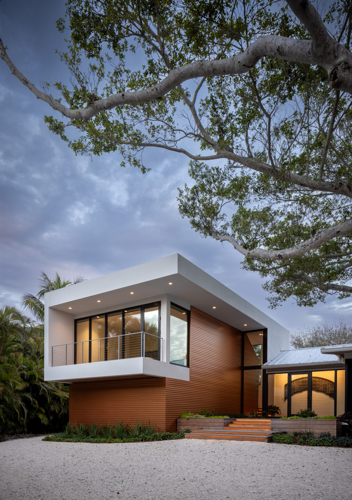 Cantilevered white box of the addition with wood siding at dusk