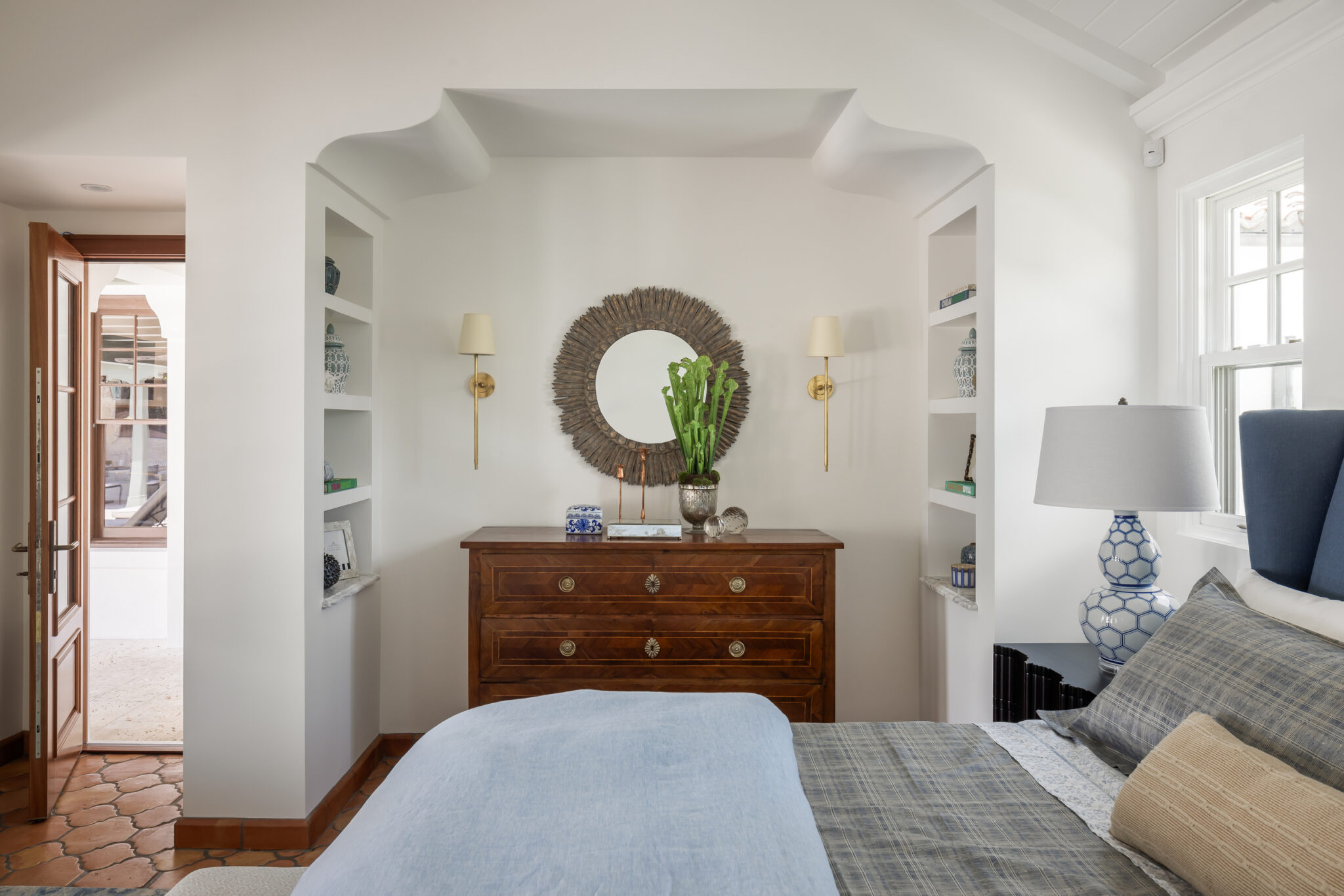 Bedroom niche with a wood dresser and round mirror