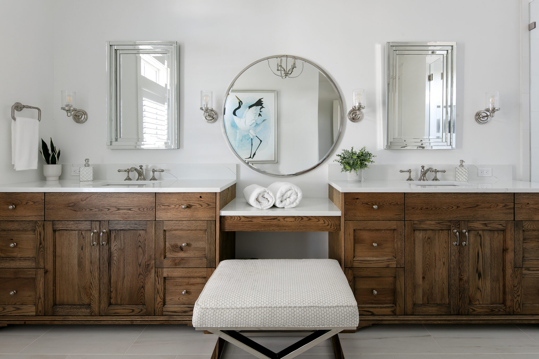 Primary bath with a wood double vanity and round mirror