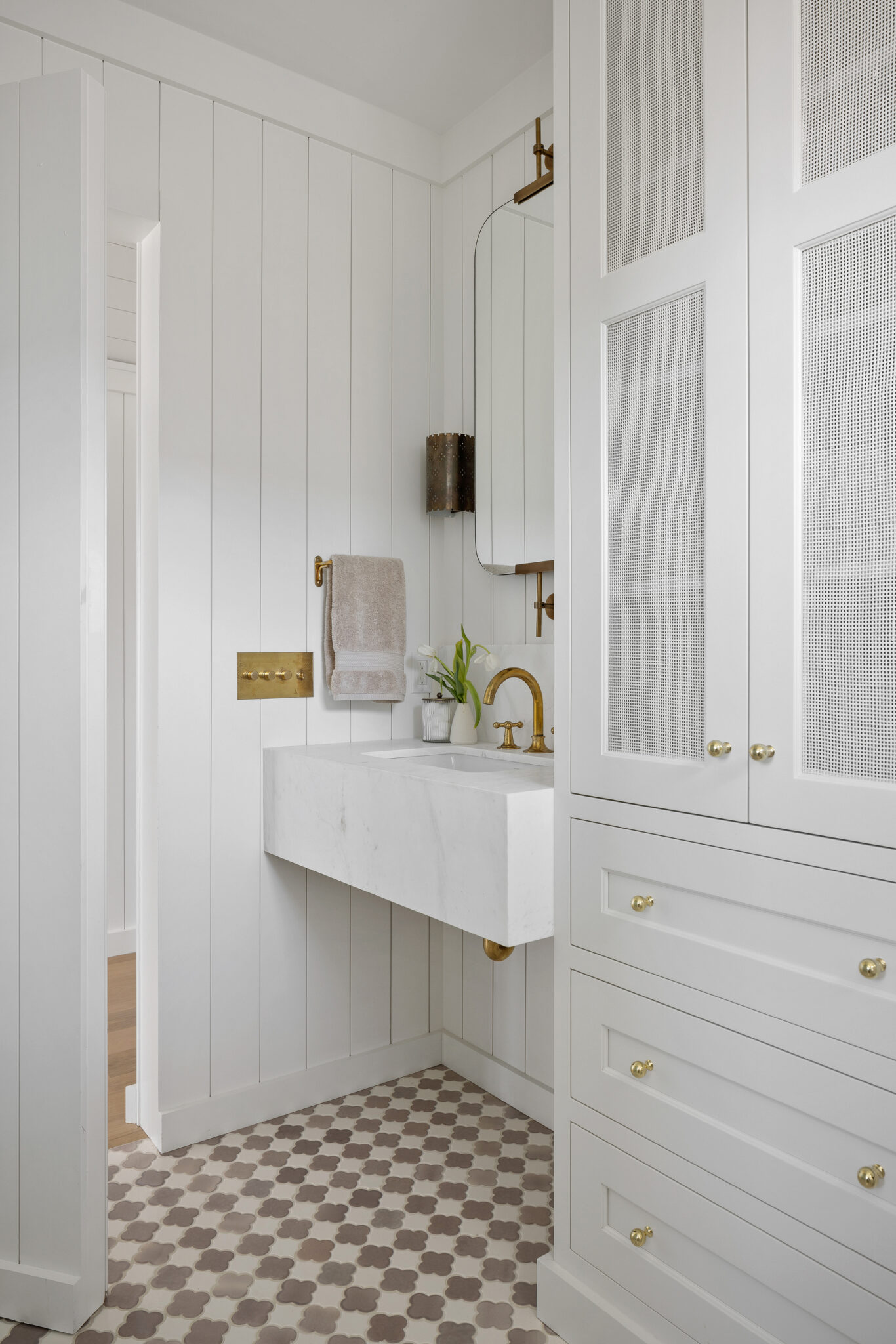Bathroom vanity with brass fixtures and checkerboard tile floor