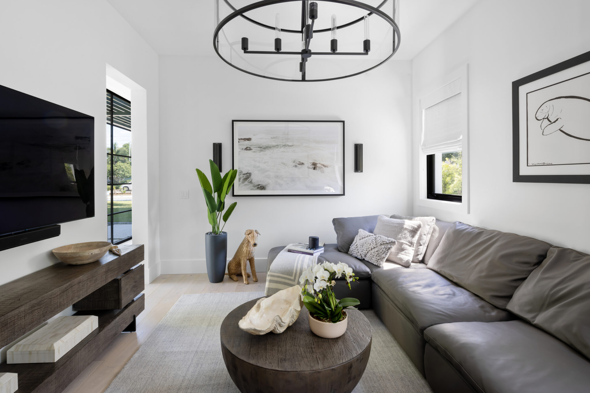 Den with a gray sectional, round coffee table and iron chandelier