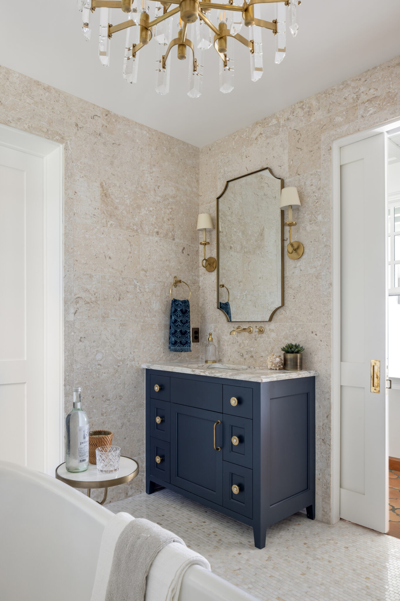 Bath with a navy vanity, stone walls and an arched mirror
