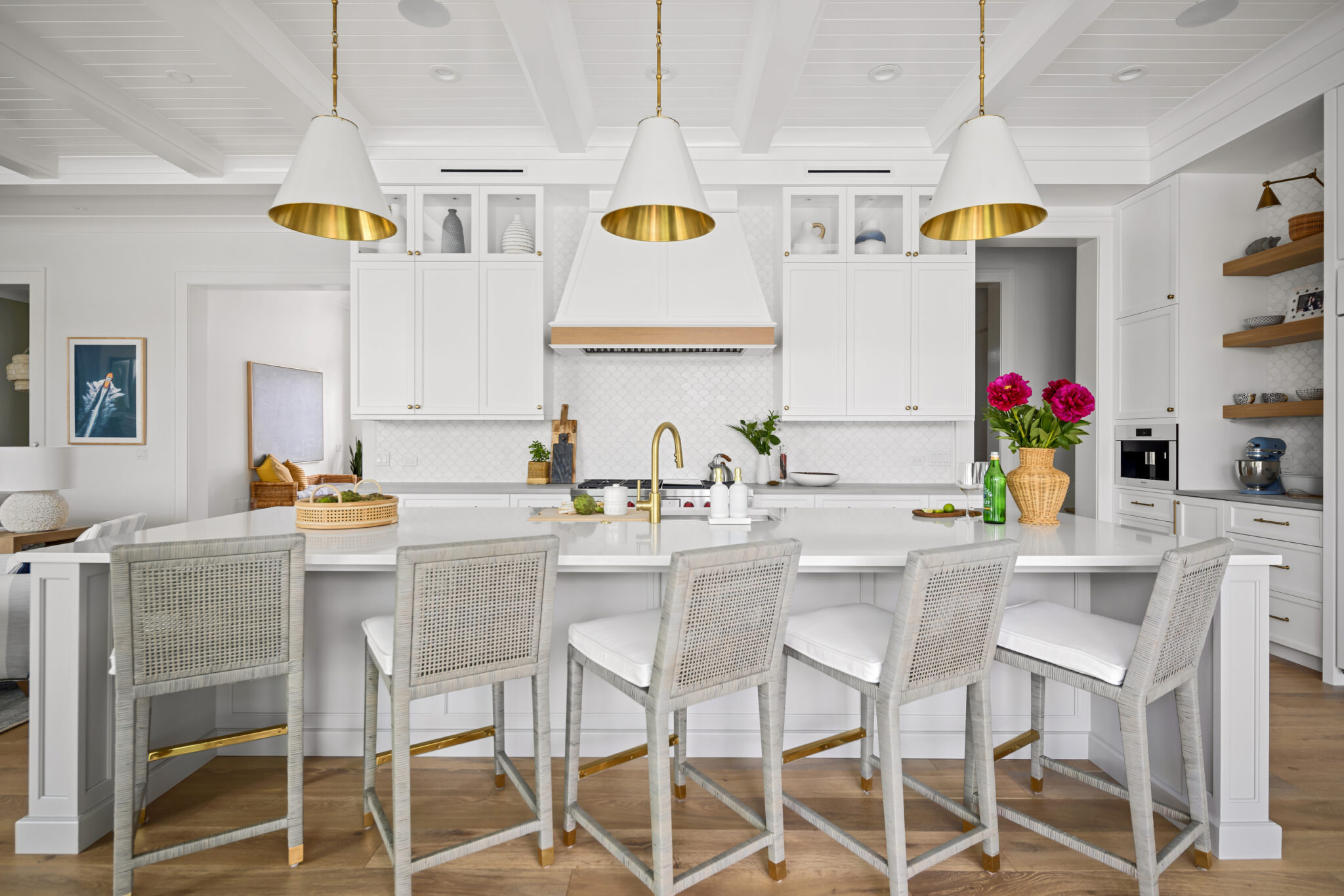 Kitchen island with woven stools under white and brass pendants