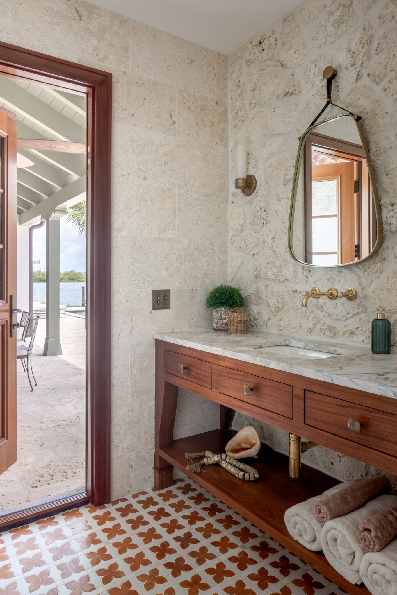 Bath vanity in wood with an arched mirror and patterned tile floor