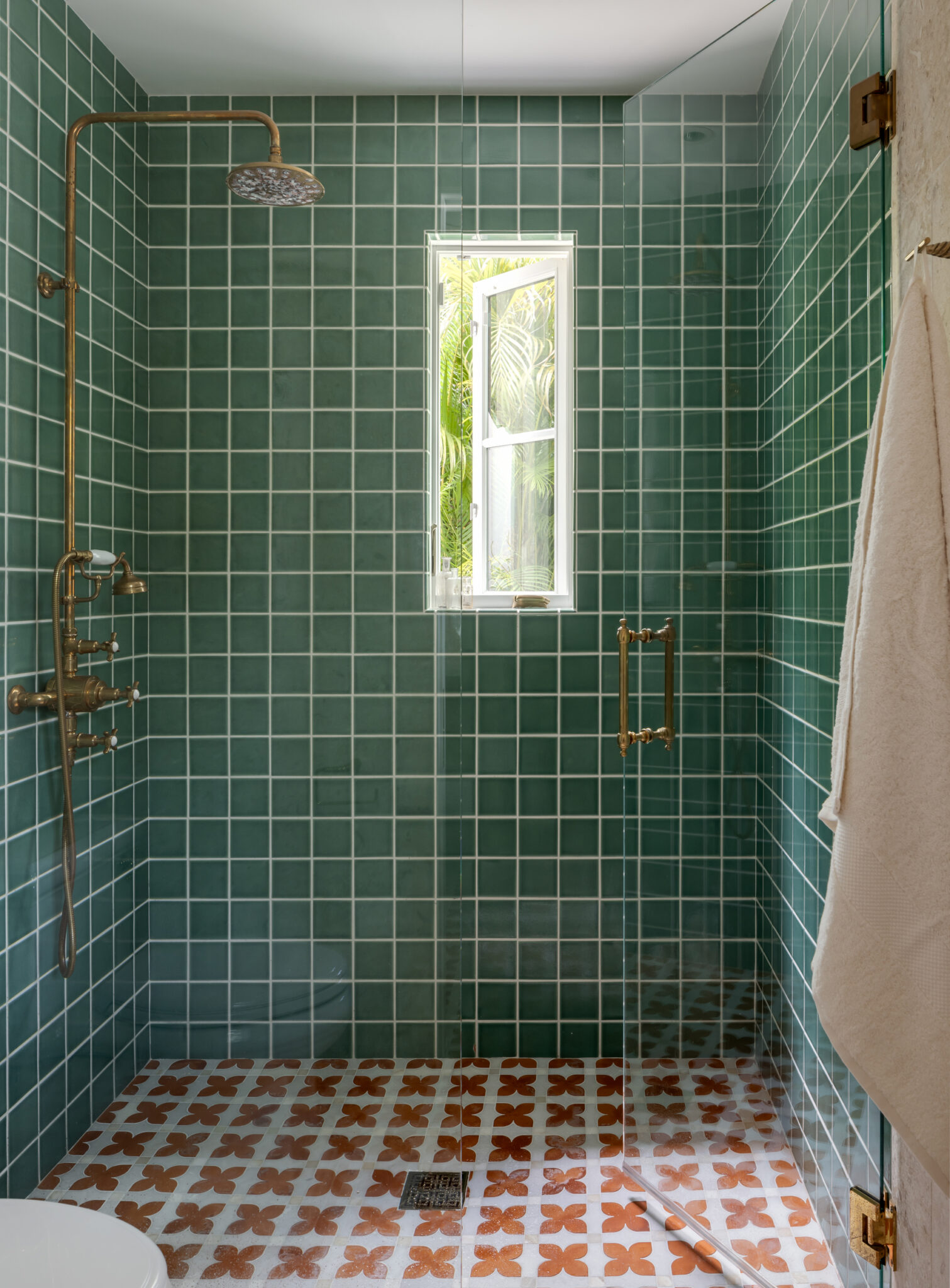 Shower with green glazed tile and a patterned floor