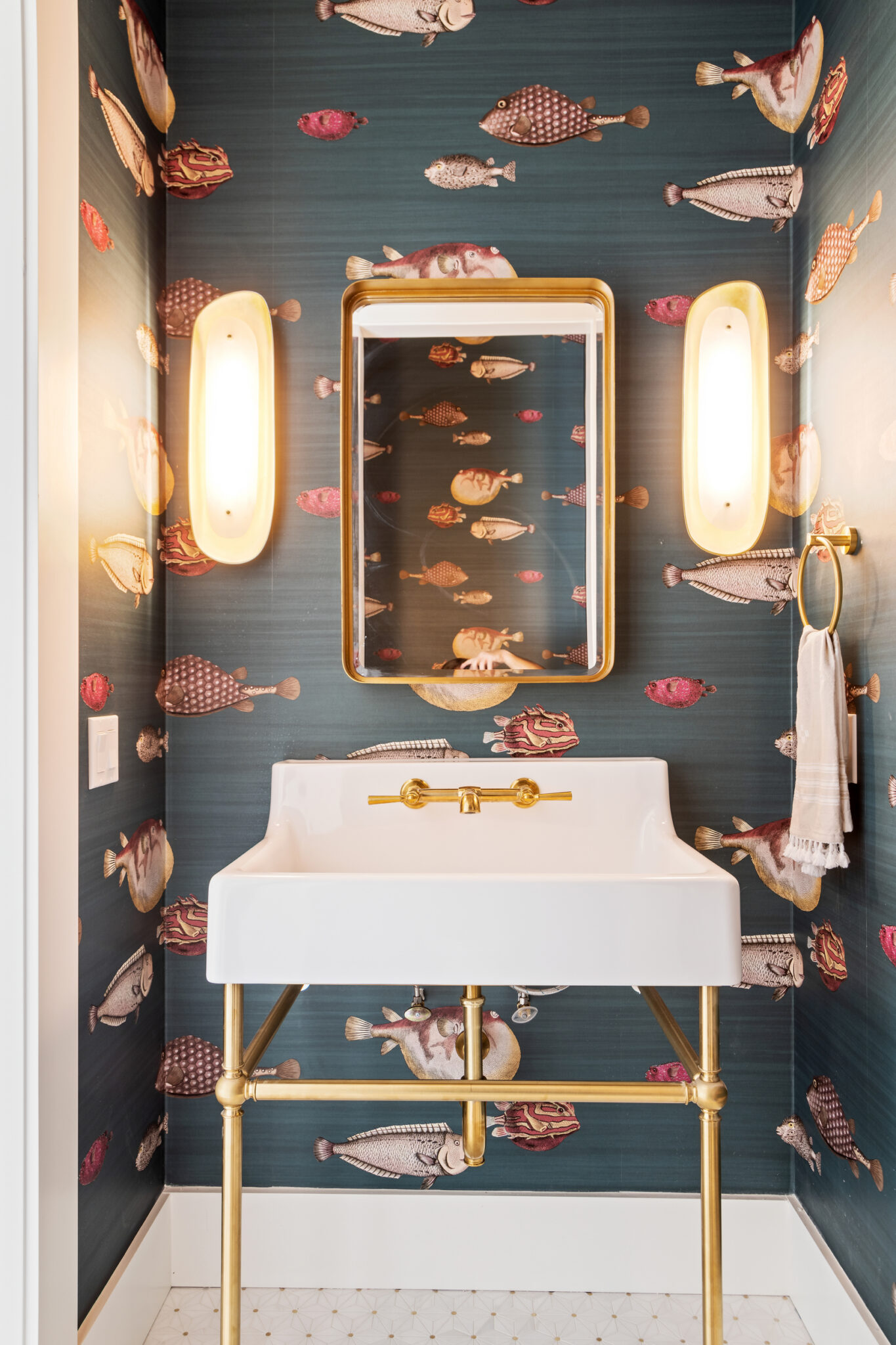 Powder room with dark fish-print wallpaper and a gold mirror