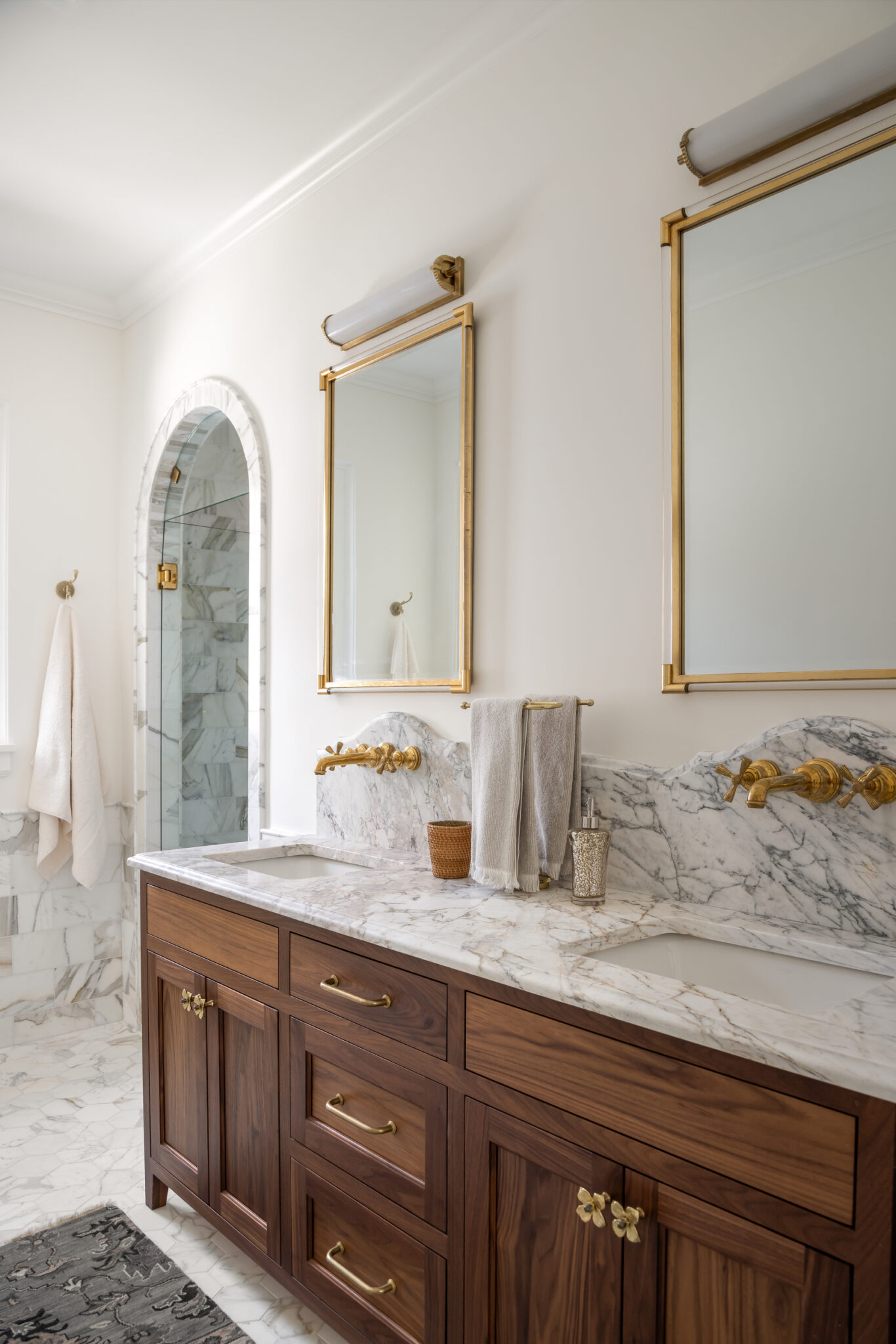 Wood double vanity with brass mirrors and marble counters