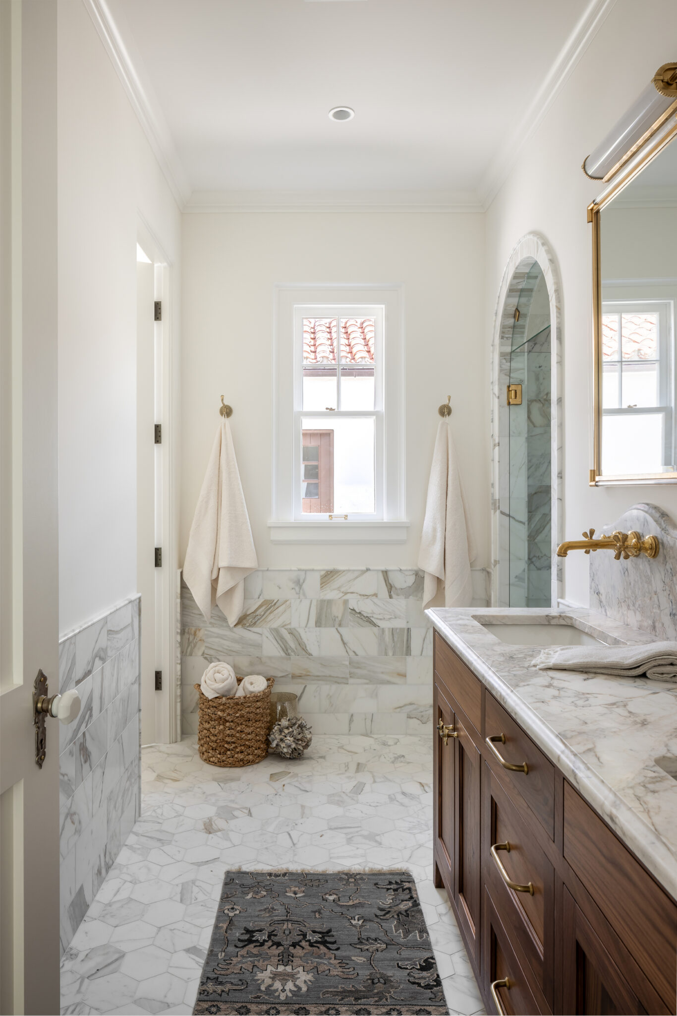 Marble bath with a wood vanity and arched shower