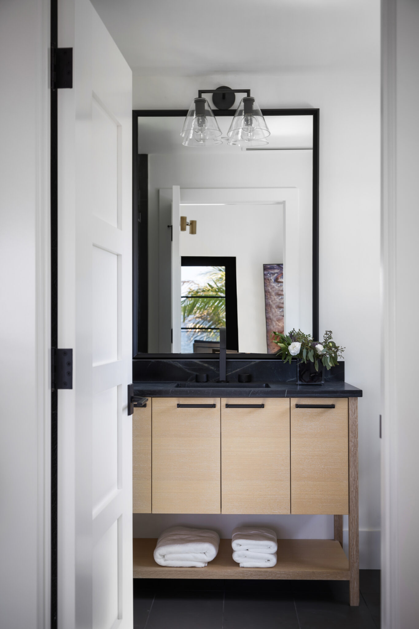 Bath with a light oak vanity and black mirror