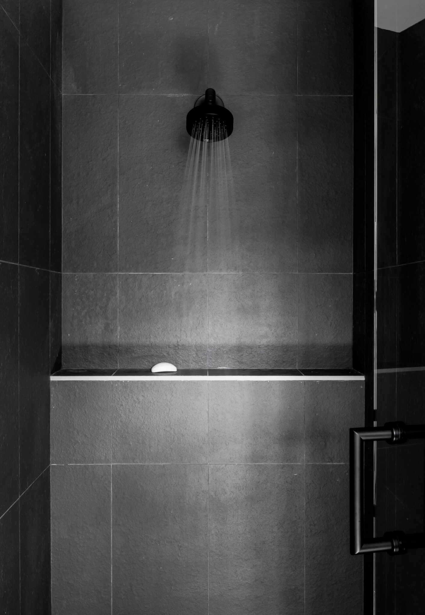 Dark tile shower with a black glass door