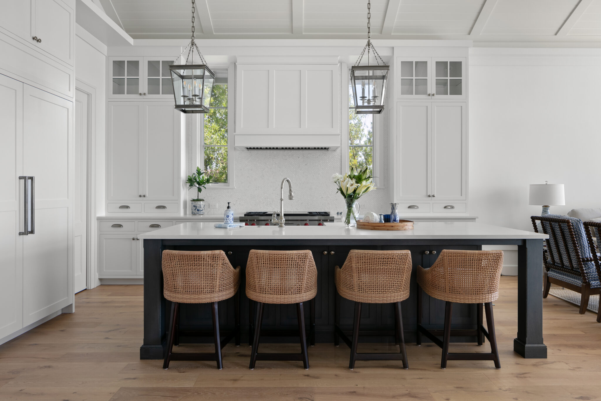 Kitchen with a black island, woven stools and lantern pendants