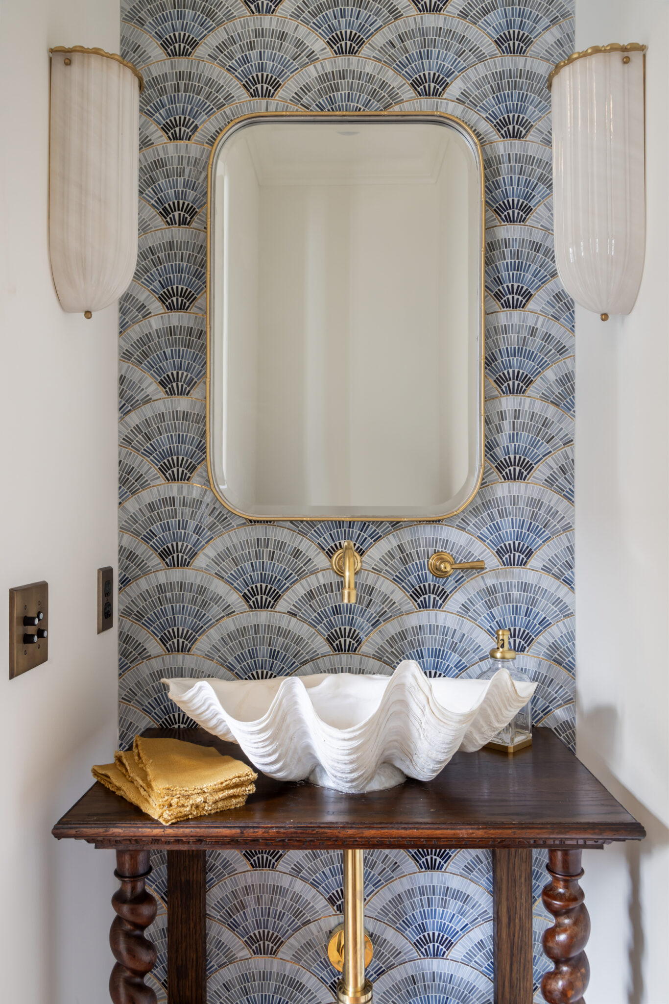 Powder room with blue scallop tile and a shell sink