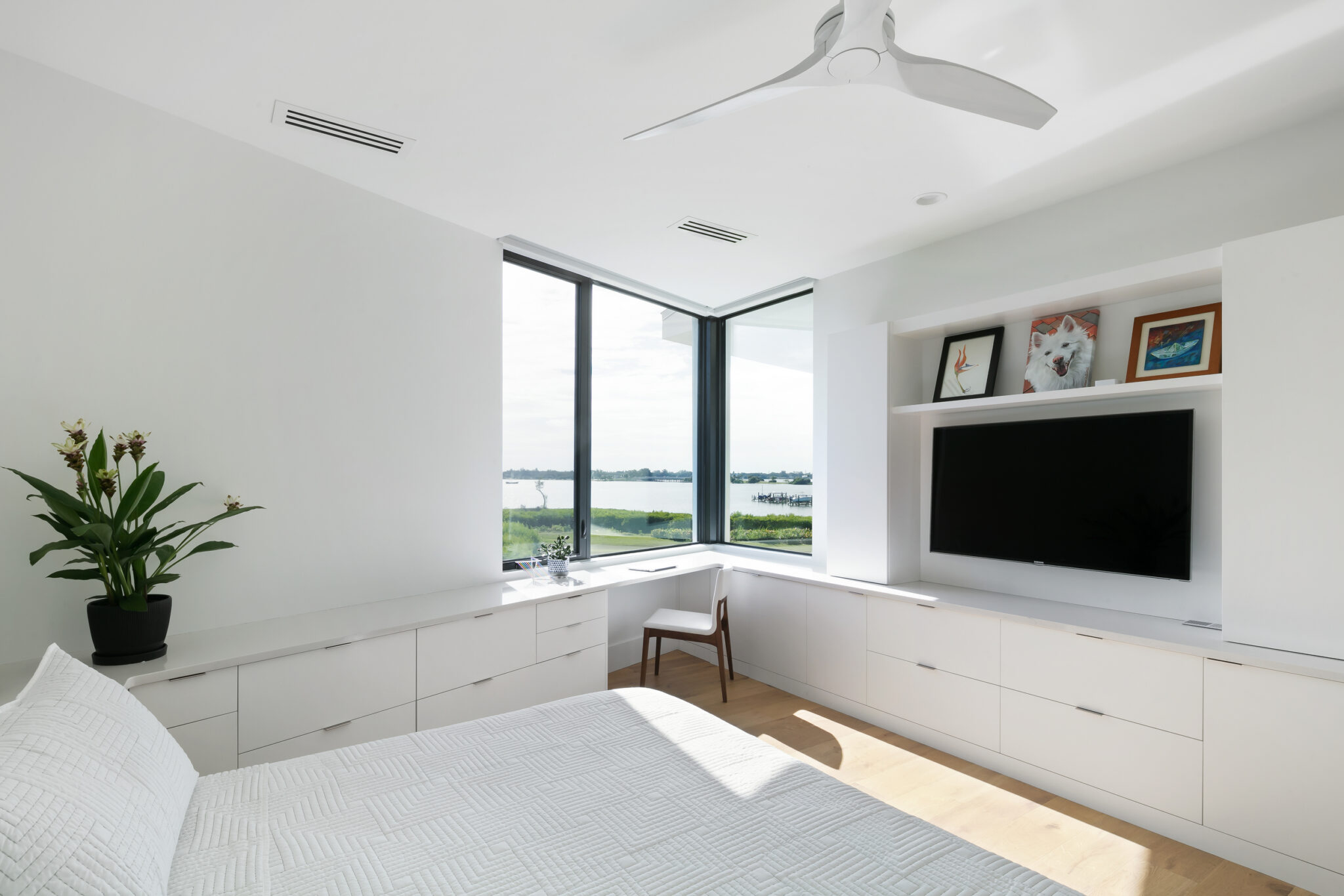 Bedroom with built-in media cabinet and corner windows to the bay