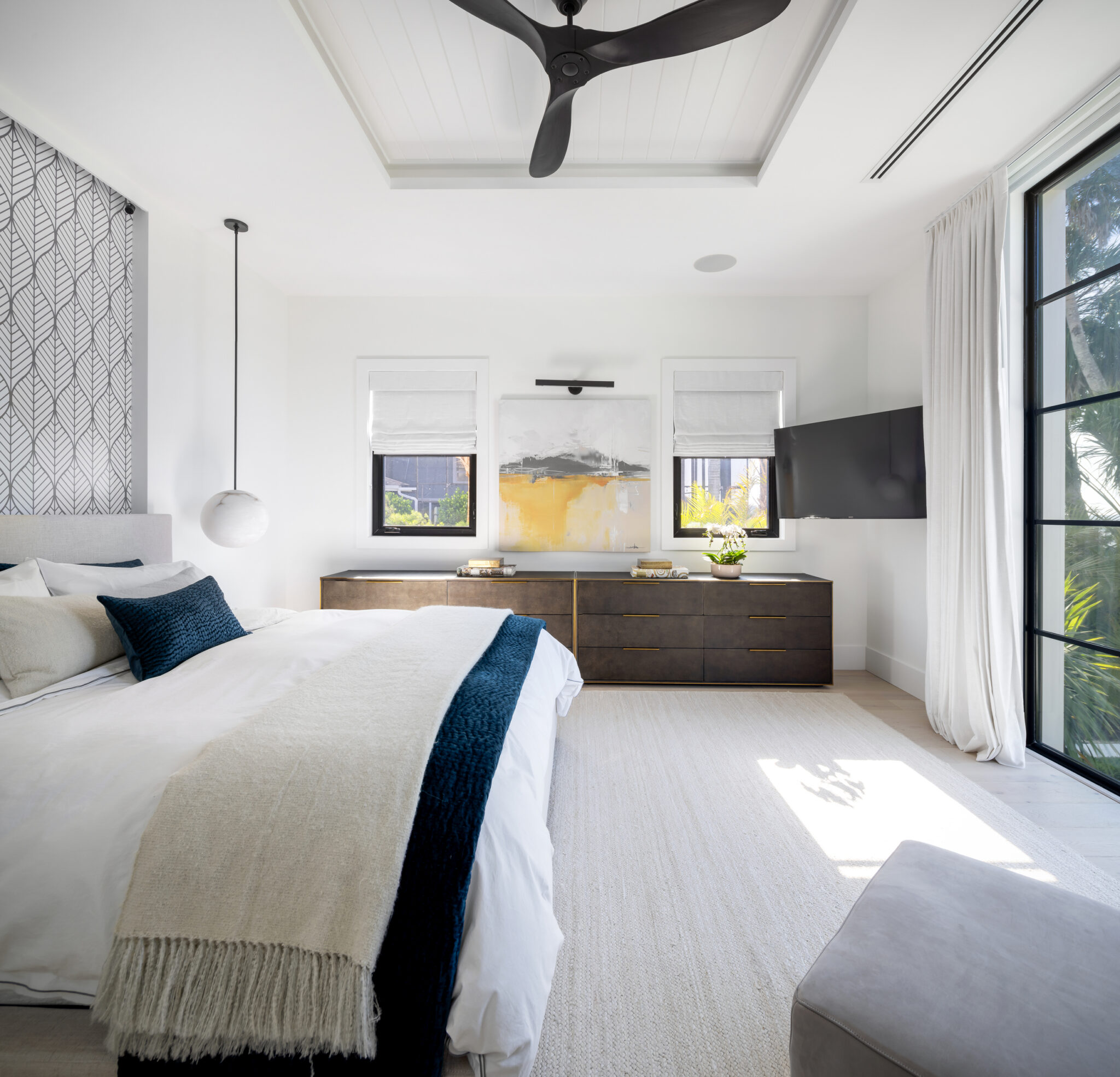 Bedroom with a white bed, navy throw and steel window