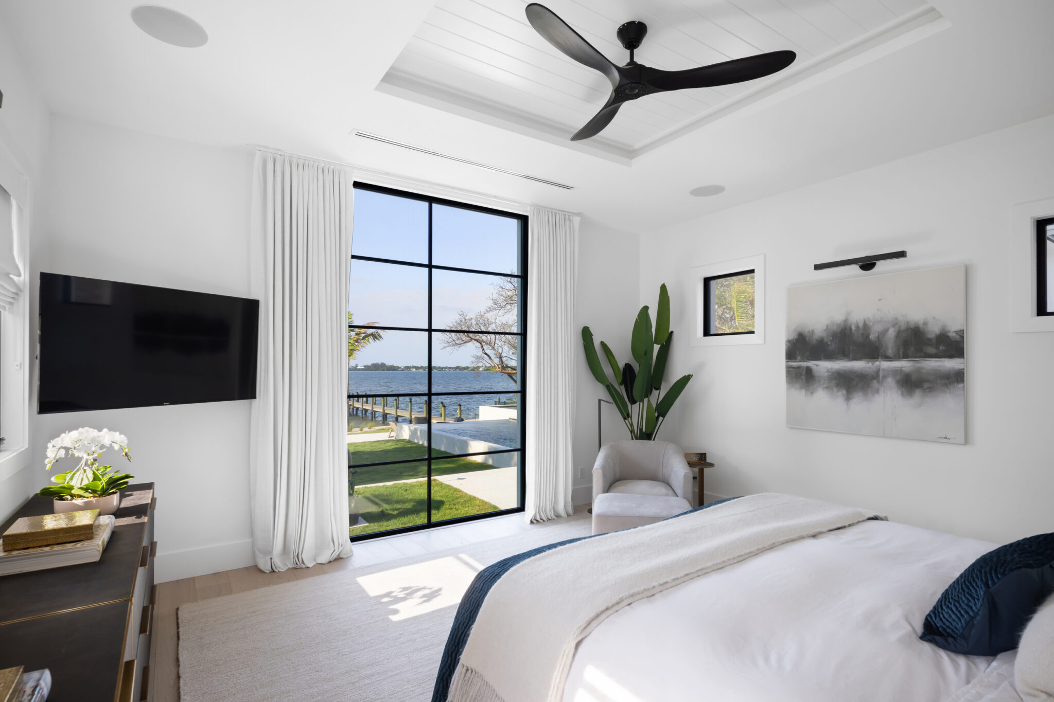 Primary bedroom with a tall steel window looking to the river