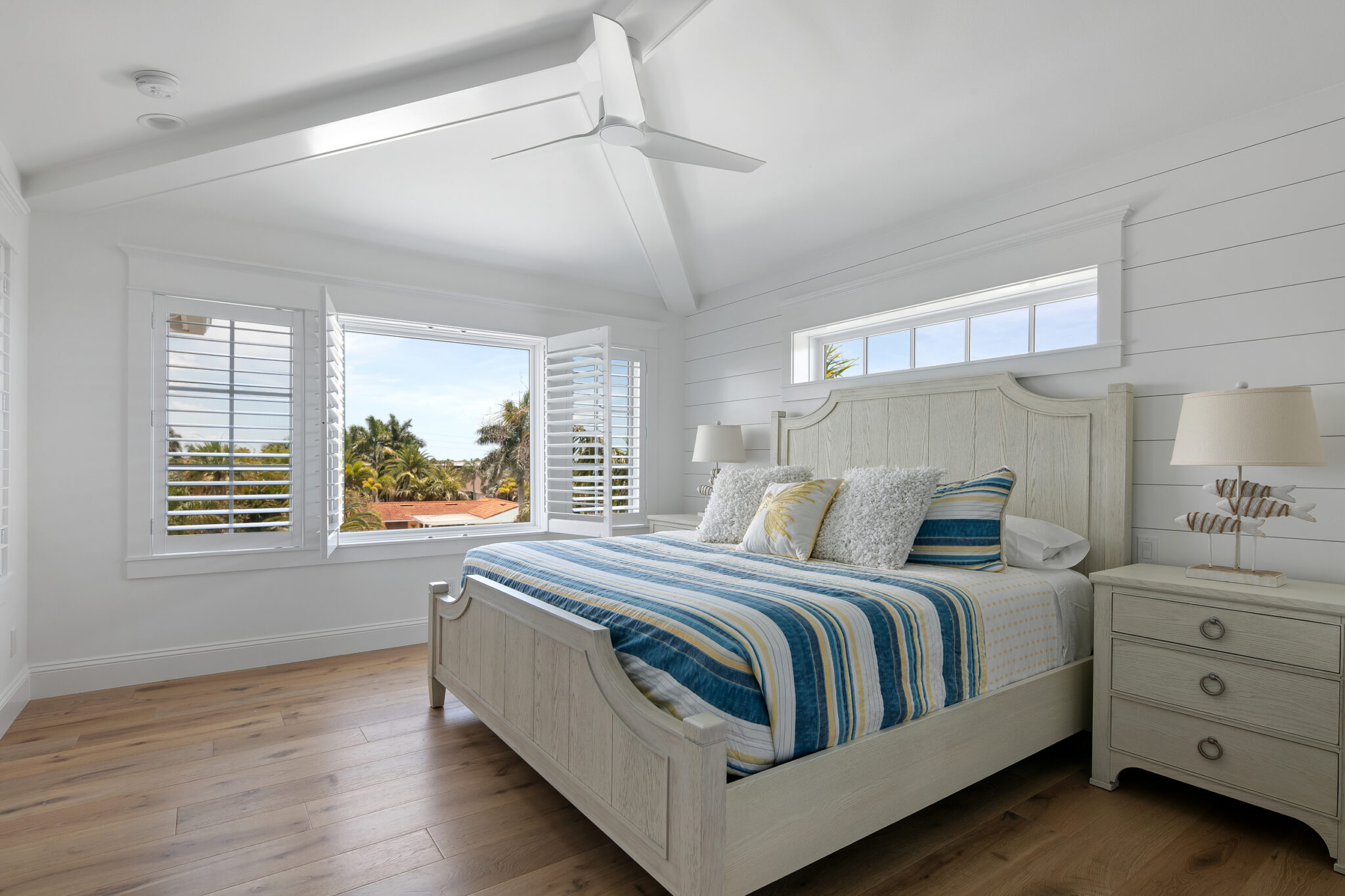 Bedroom with a striped bedspread and plantation shutters