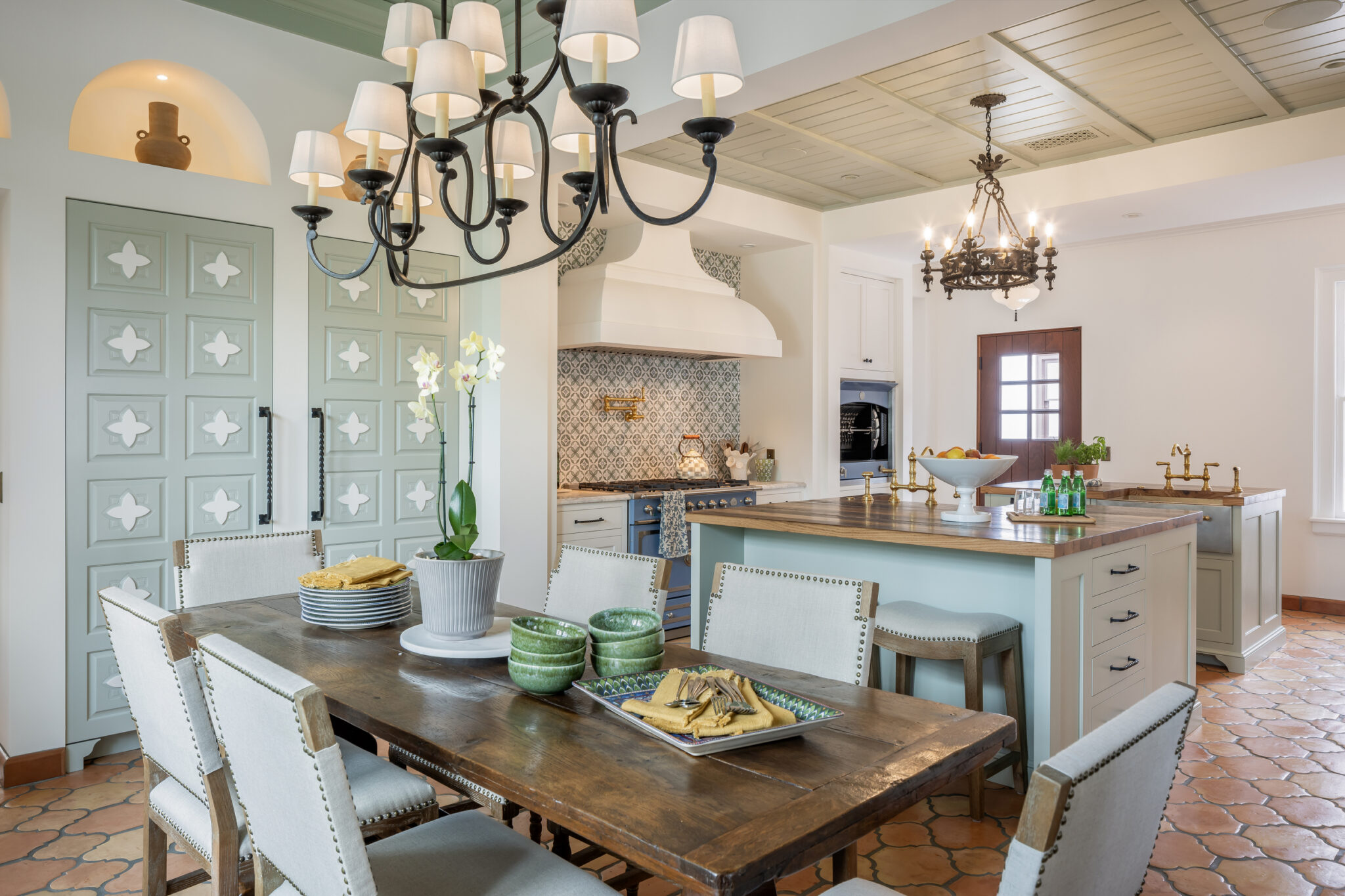 Dining table and kitchen island under a painted wood ceiling