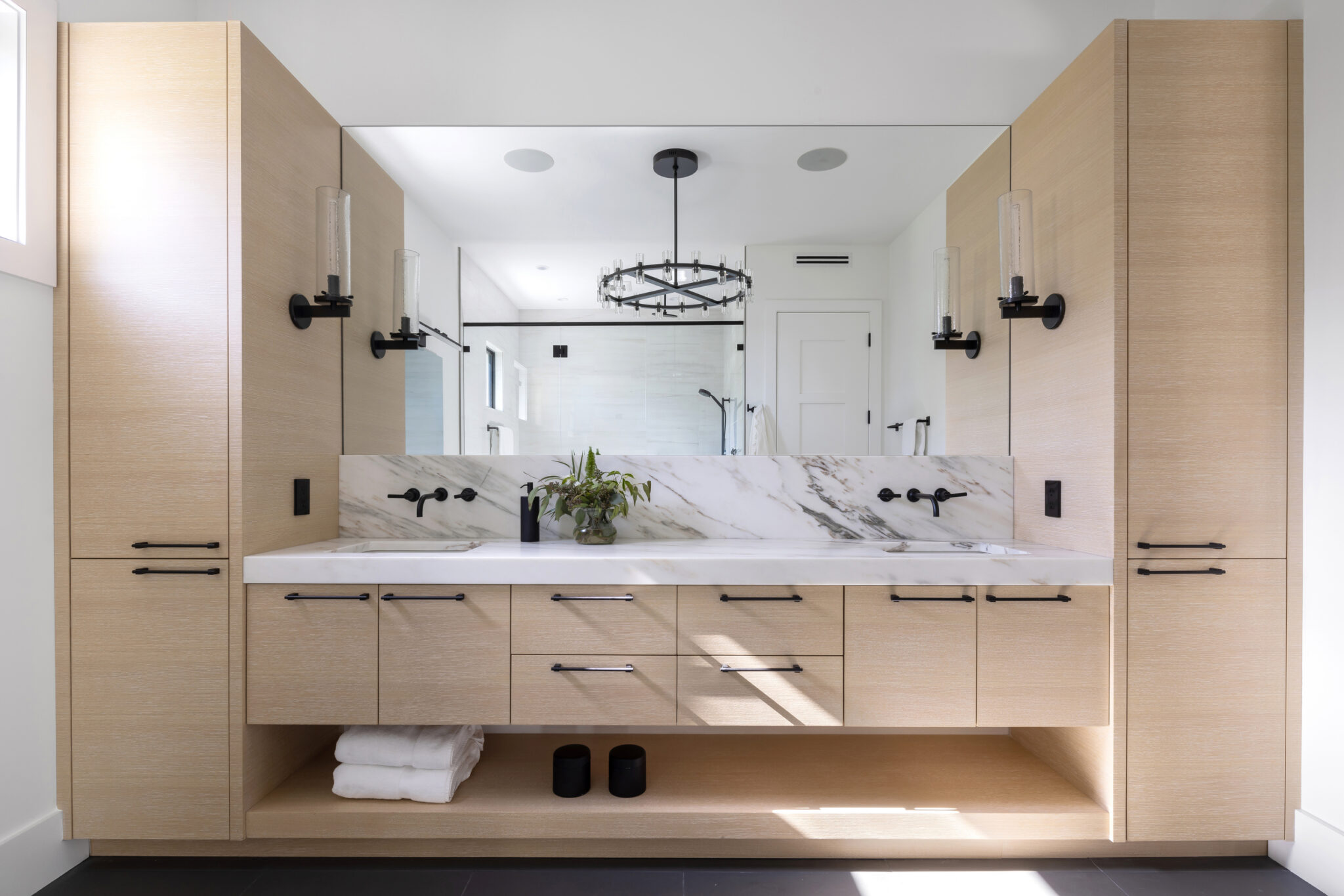 Primary bath with a long oak vanity and marble backsplash