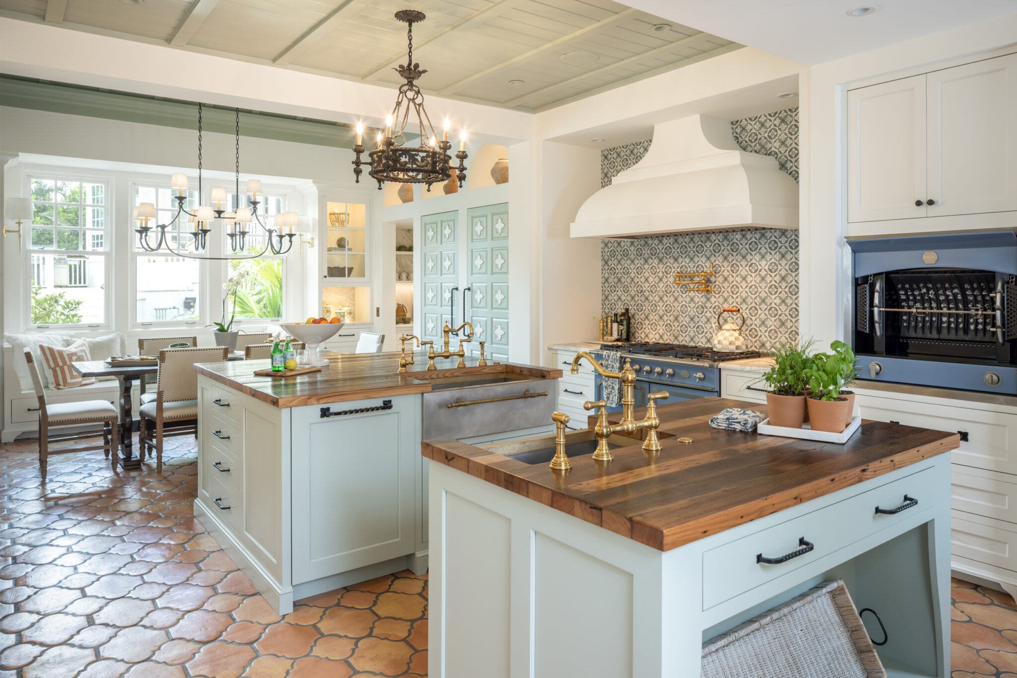 Kitchen islands with wood tops and a blue range under a plaster hood