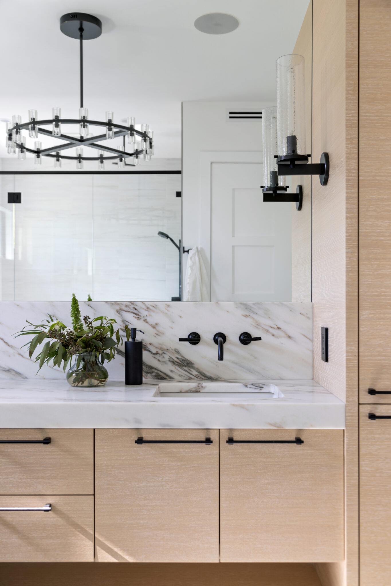 Bath vanity with oak cabinets and a ring chandelier