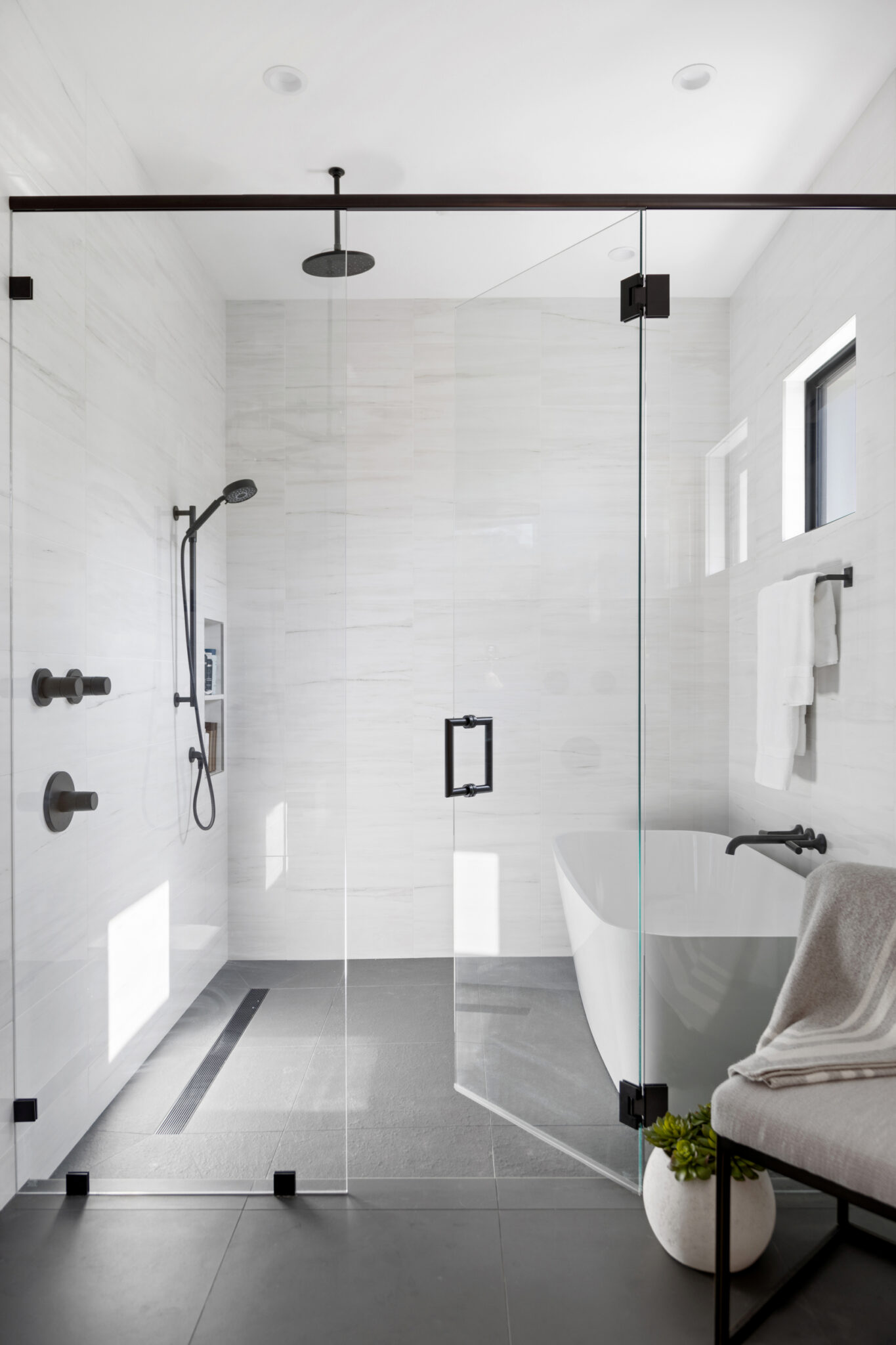 Walk-in glass shower with gray tile floor