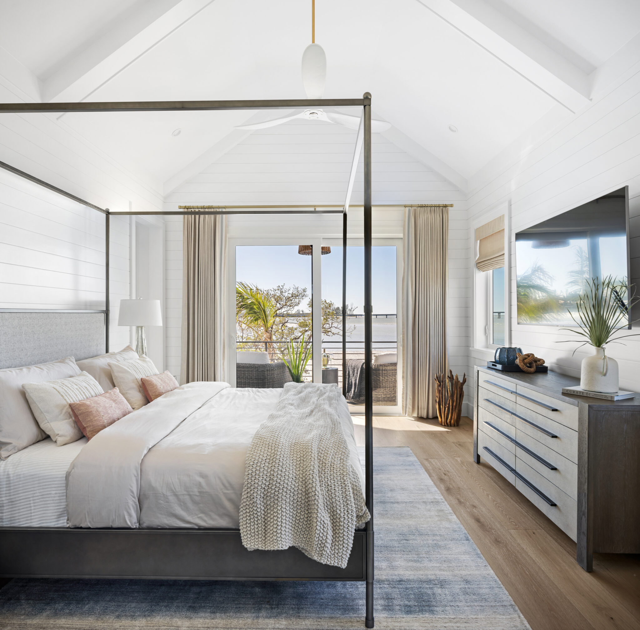 Bedroom with a black canopy bed and water view